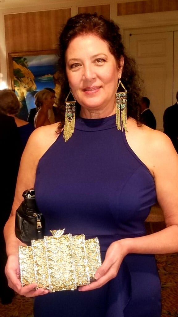 woman wearing a blue dress and holding a gold and silver purse