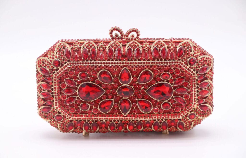 Intricately designed red gemstone-studded clutch purse with ornate patterns.